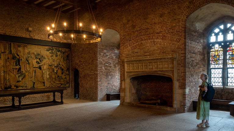 A woman looking at the wall hangings inside Tattershall Castle.